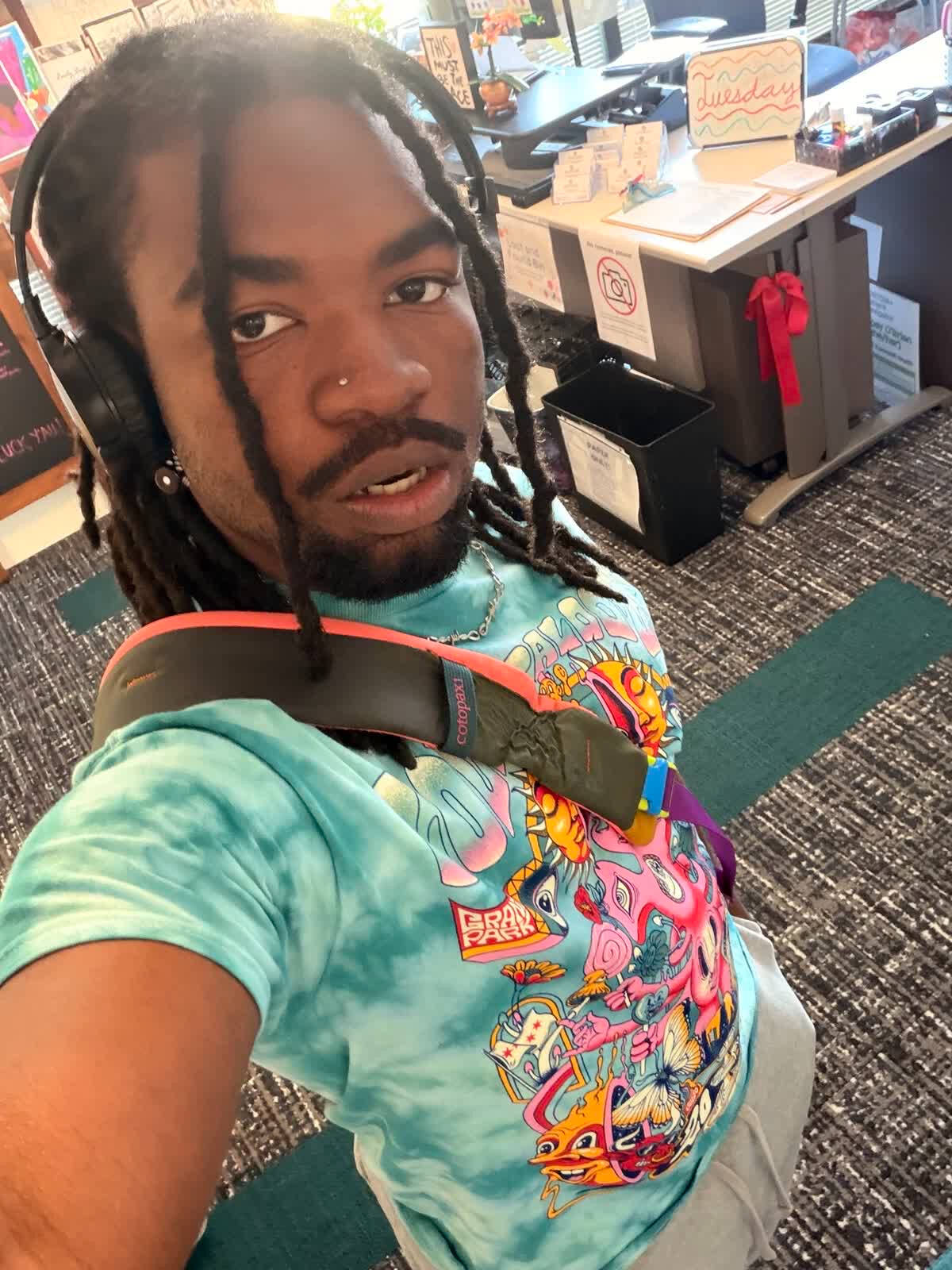 Isaiah in a bright tie-dye shirt in the Rainbow Resource Center